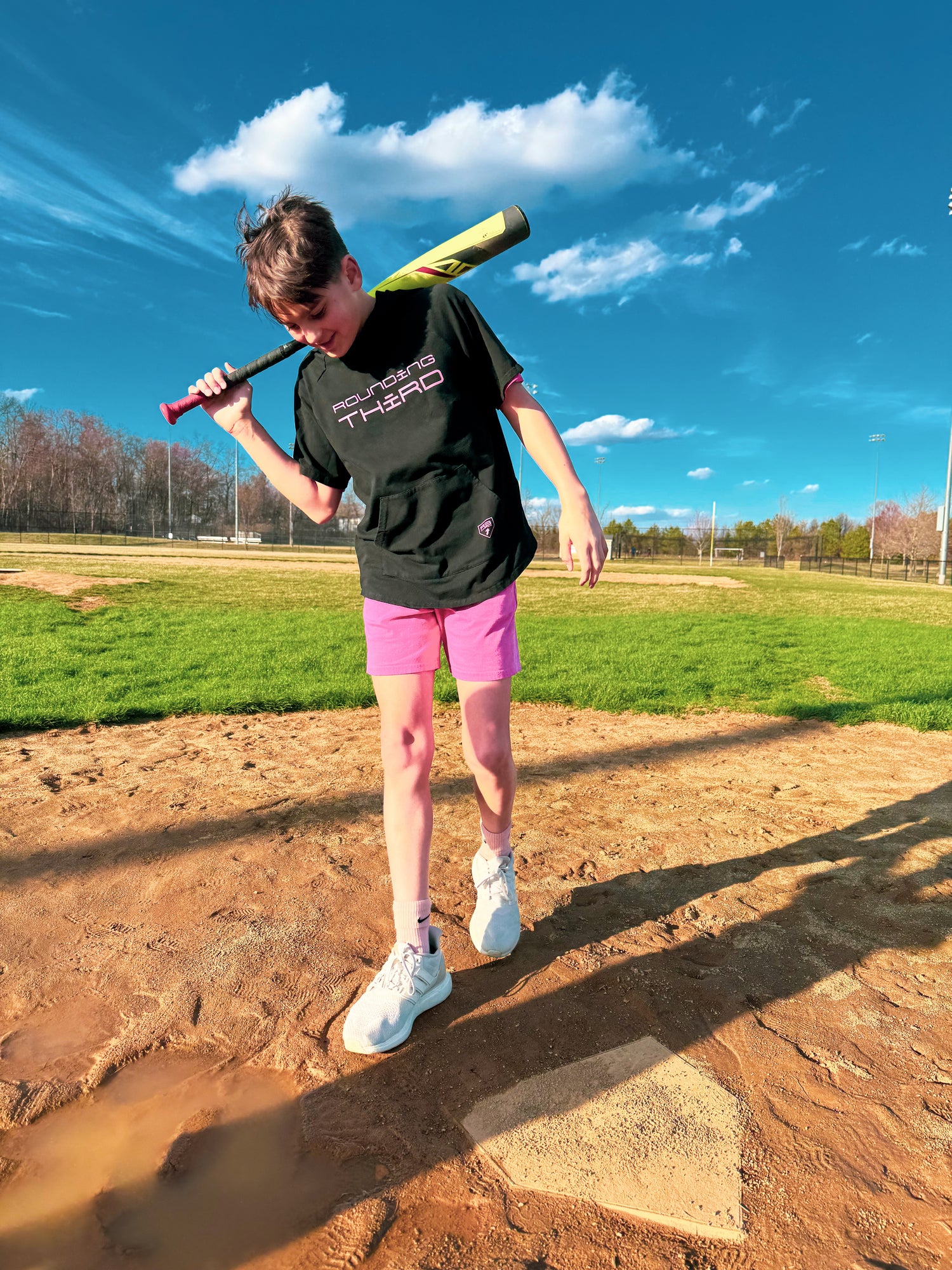 boy with bat at baseball field sunny skies